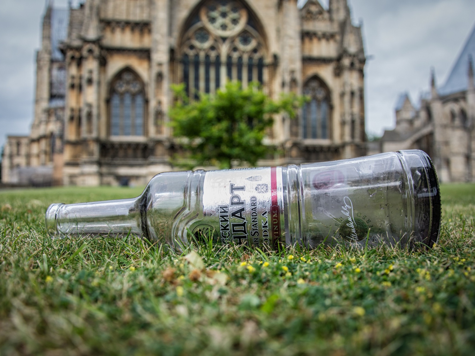 Пустая бутылка на газоне перед храмом