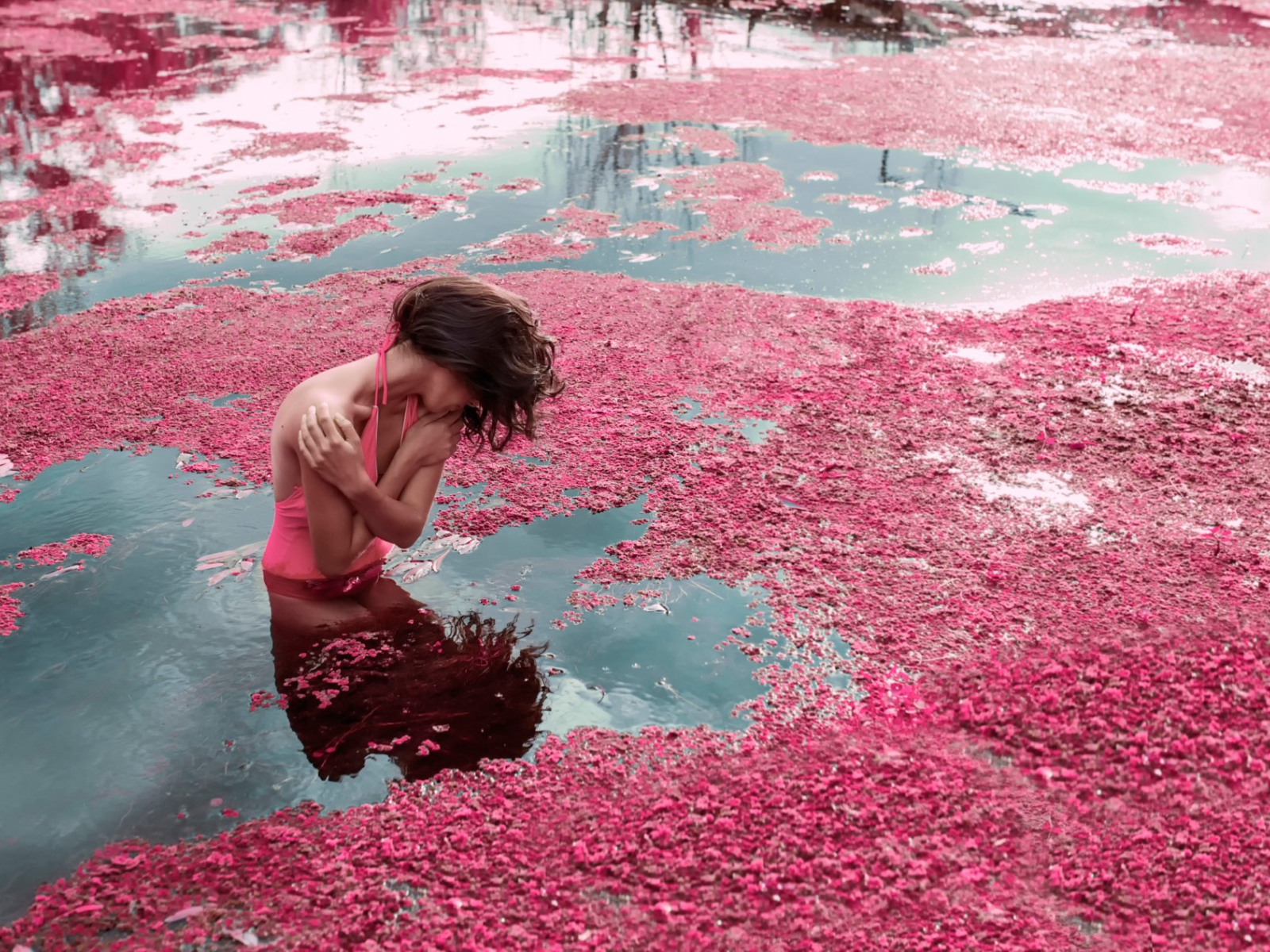 Девушка стоит в воде среди розовых лепестков