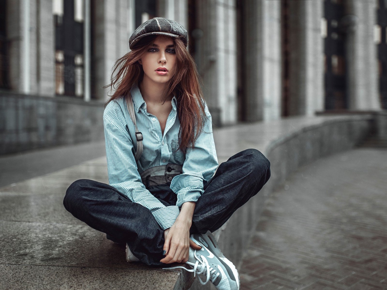 Девушка в берете сидит на краю дорожки