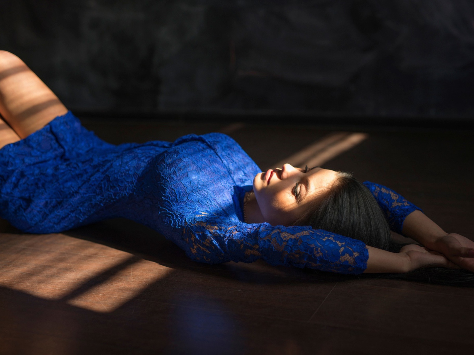 Девушка в голубом кружевном платье лежит на полу