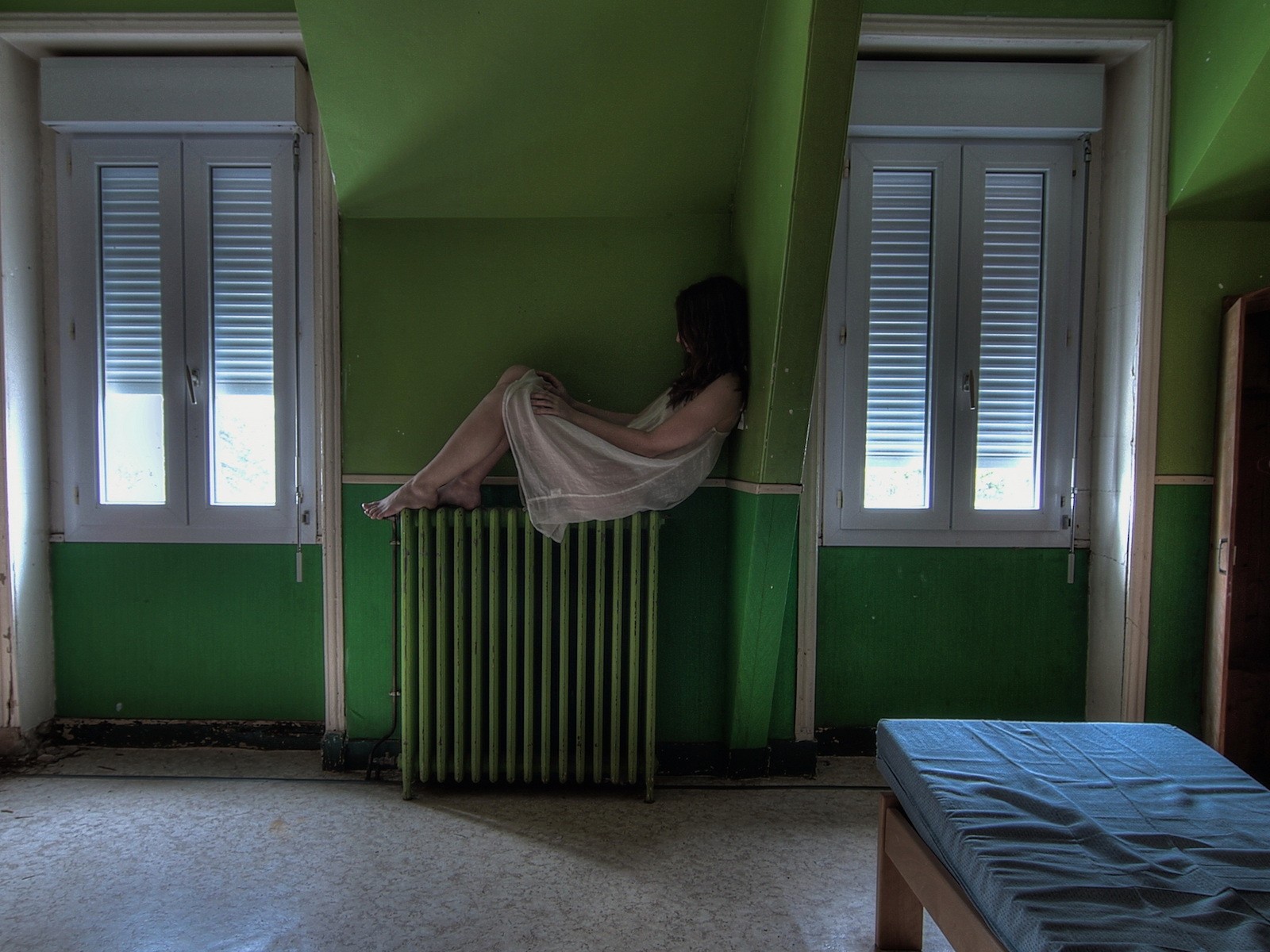 Девушка в ночной рубашке сидит на батарее