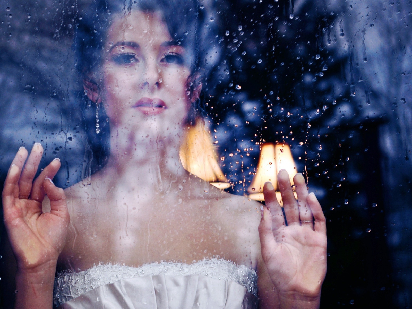 Девушка в белом платье за мокрым стеклом
