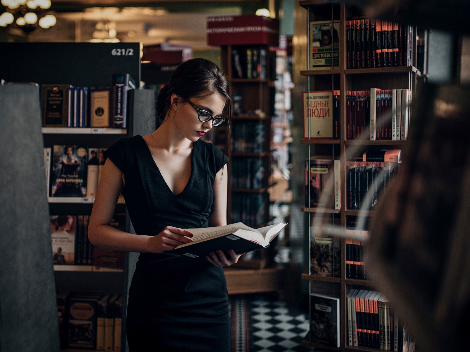 Девушка читает среди книжных полок