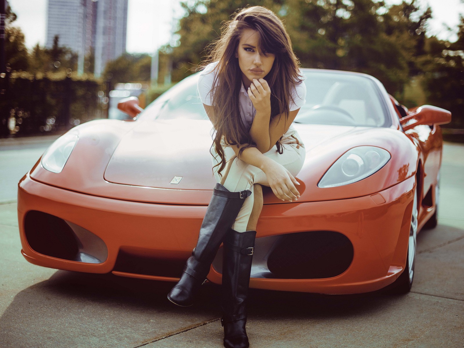 Девушка сидит на капоте оранжевого Ferrari