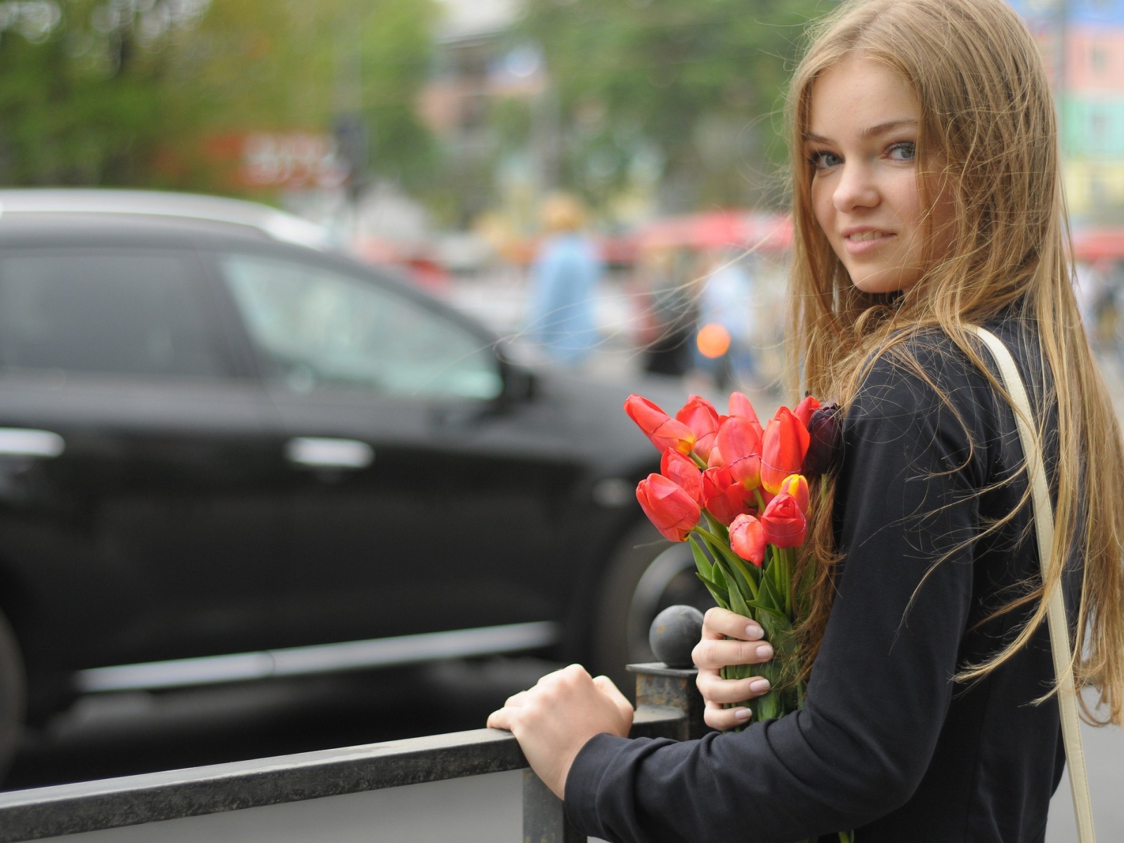 Девушка с букетом тюльпанов стоит у забора