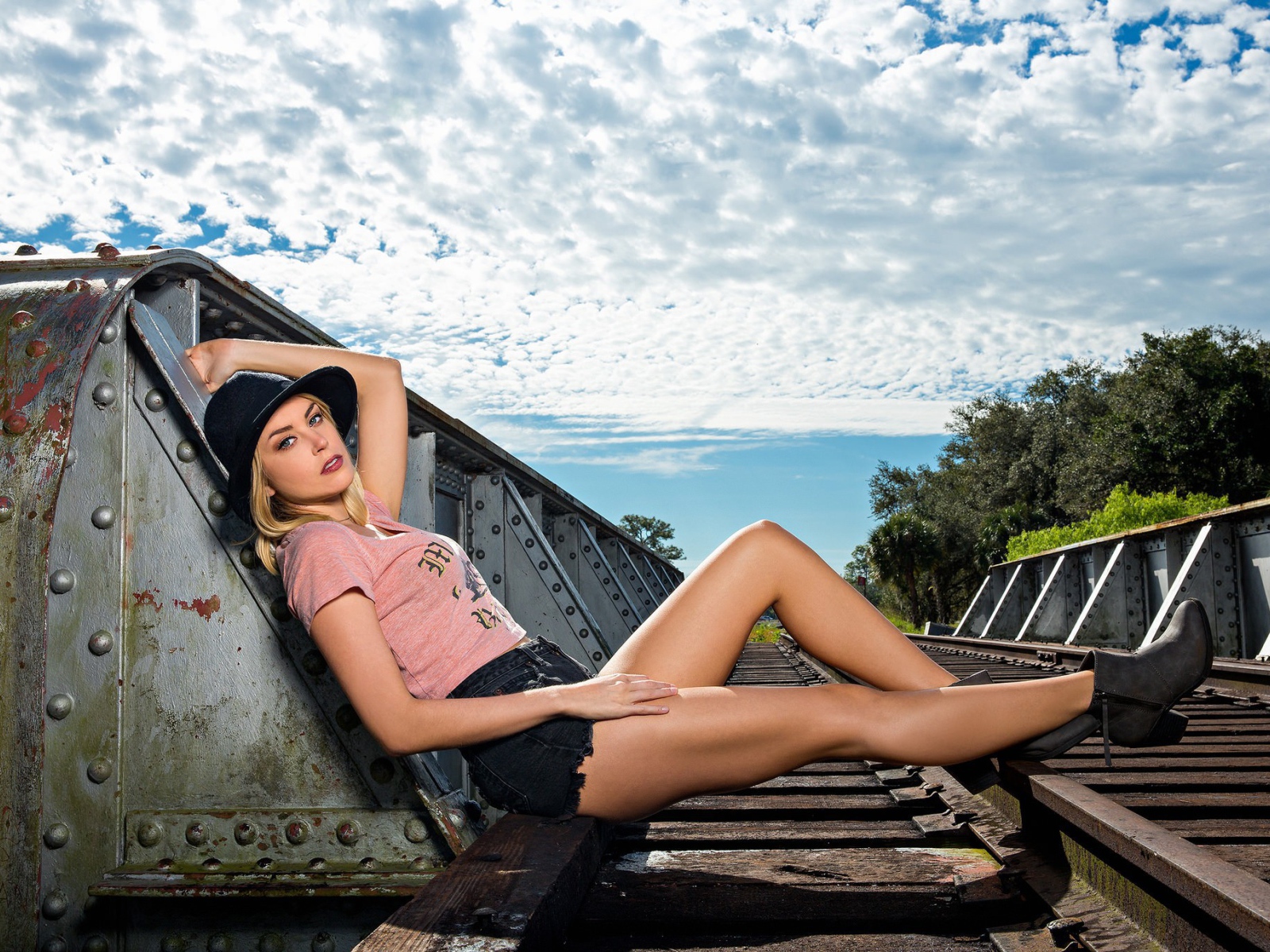 Блондинка в шляпе позирует на железной дороге