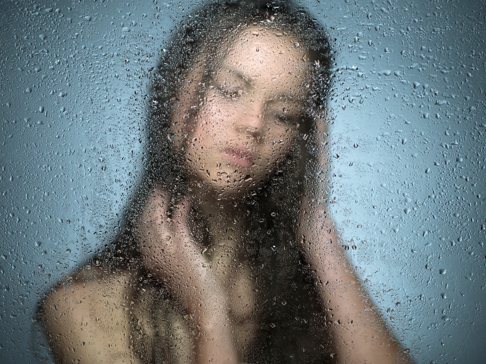 Девушка позади мокрого стекла
