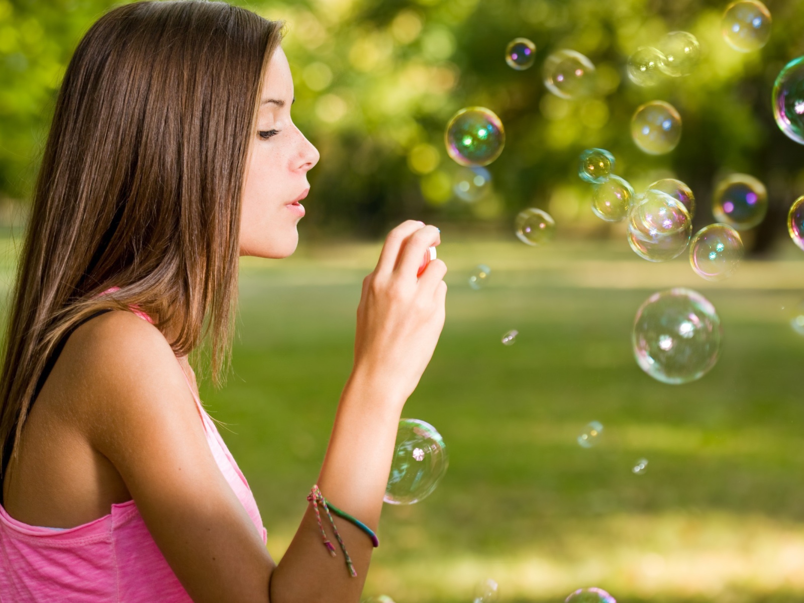 Девушка в розовой футболке запускает мыльные пузыри