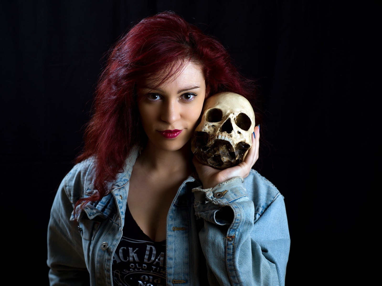 Девушка в джинсовой куртке держит череп на плече