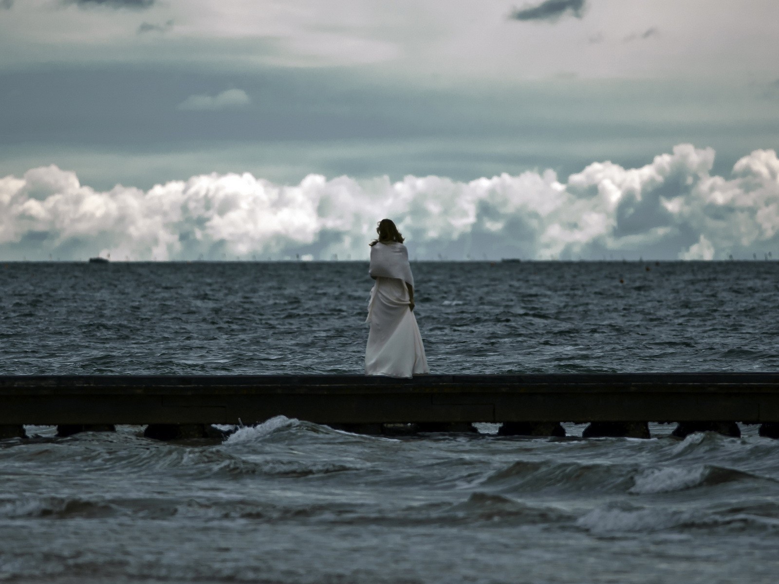 Девушка смотрит на свинцовые воды моря