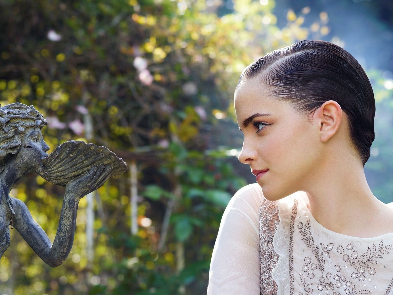 Девушка смотрит на скульптуру в саду