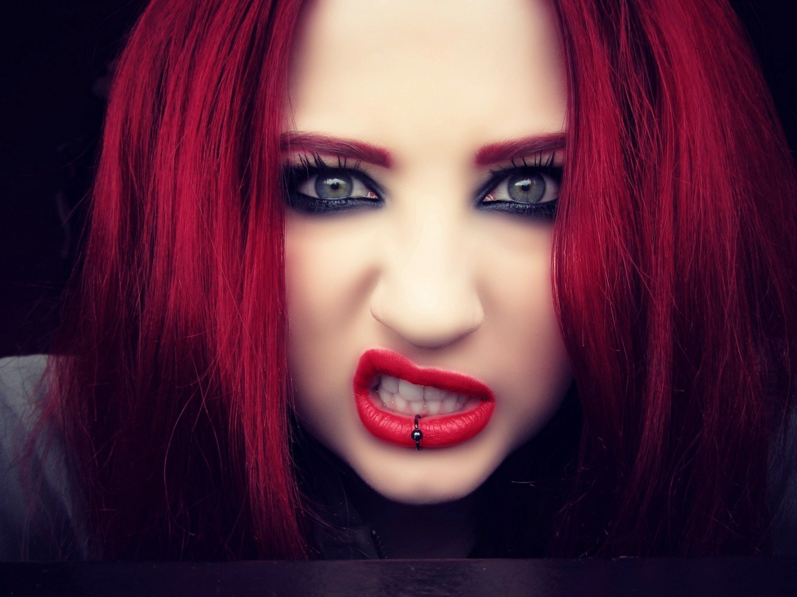 Девушка с красными волосами показывает зубы