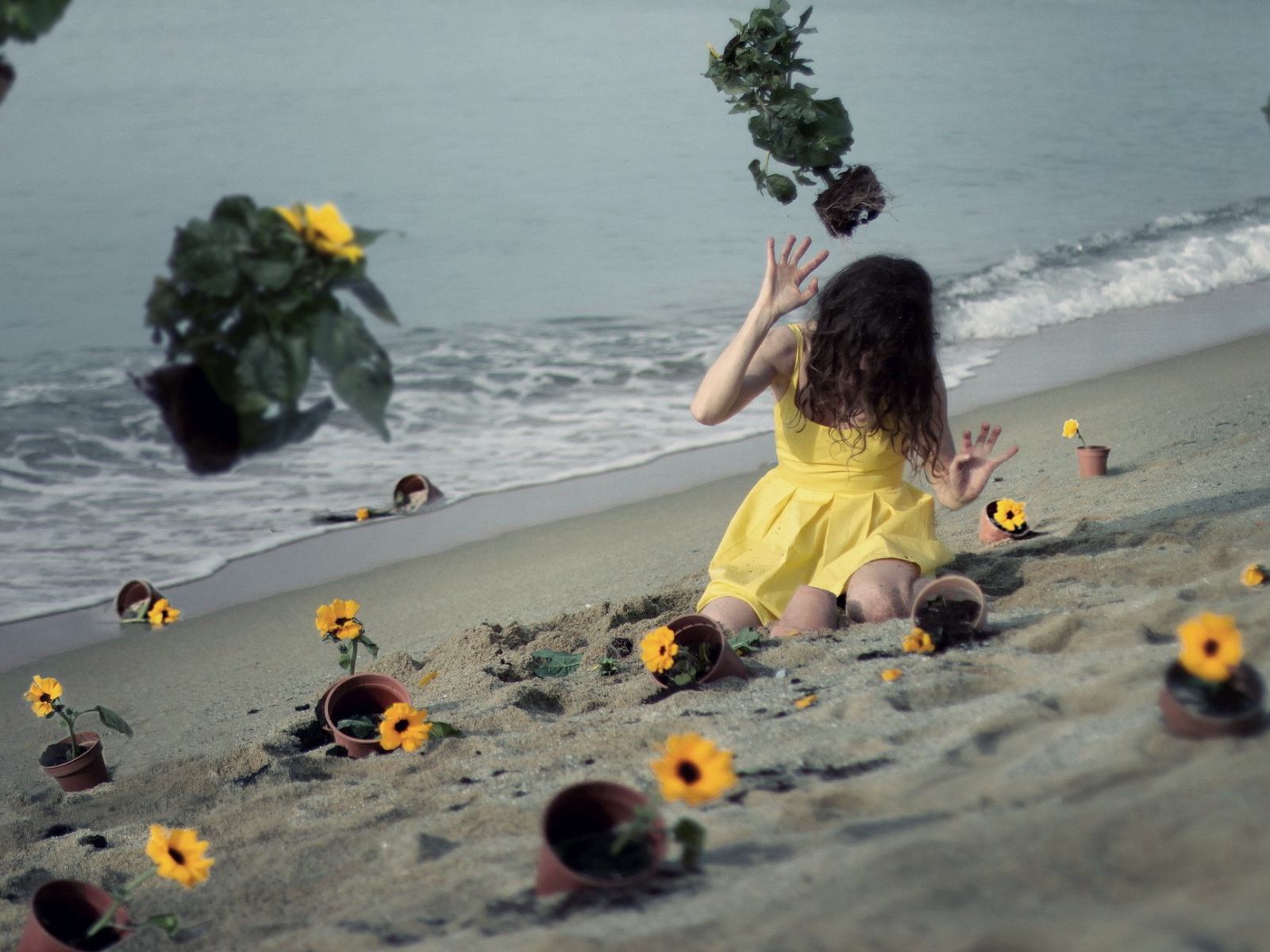 Модель в желтом платье среди цветов на пляже