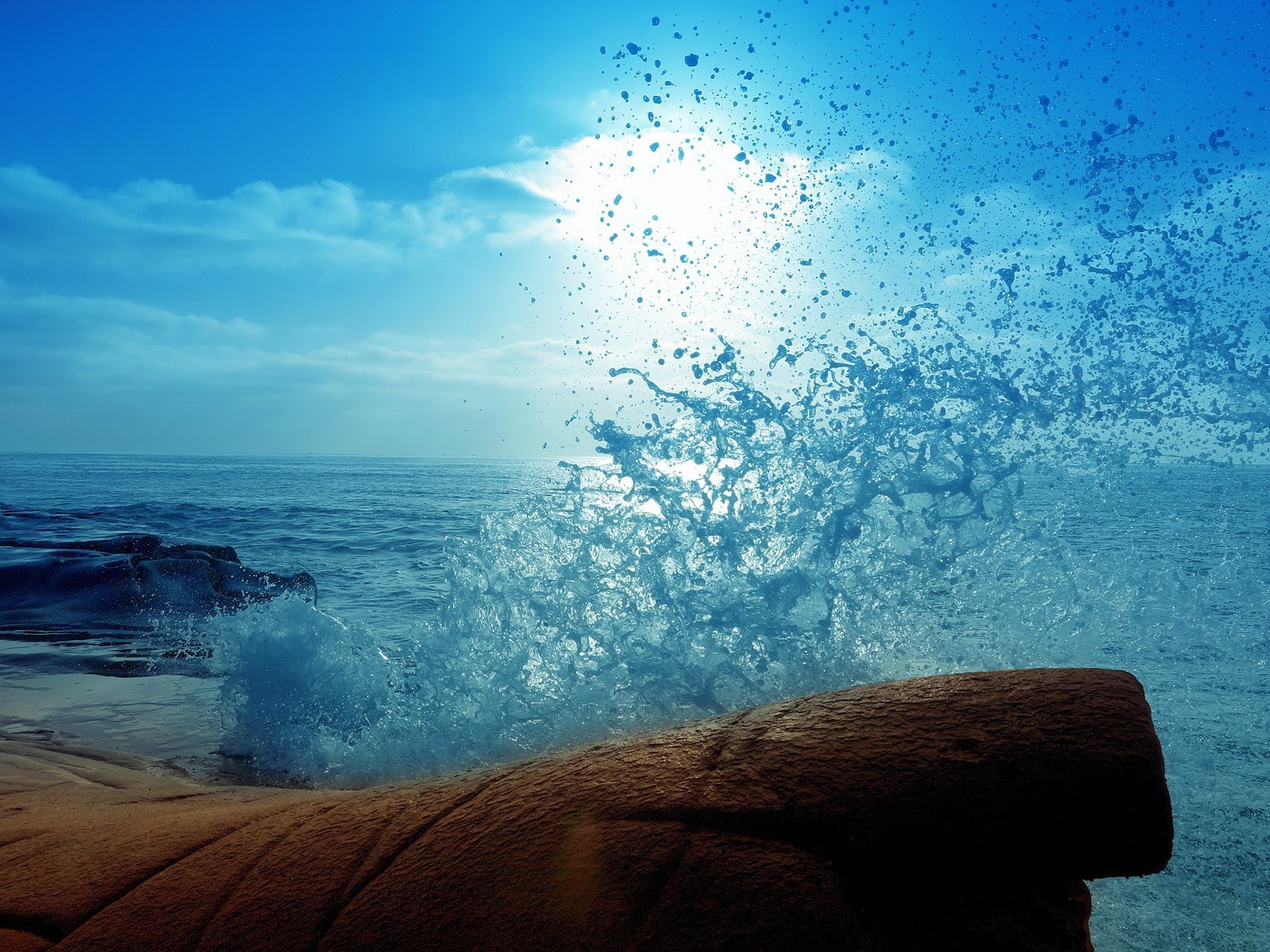 Голубая волна разбилась о камень на берегу