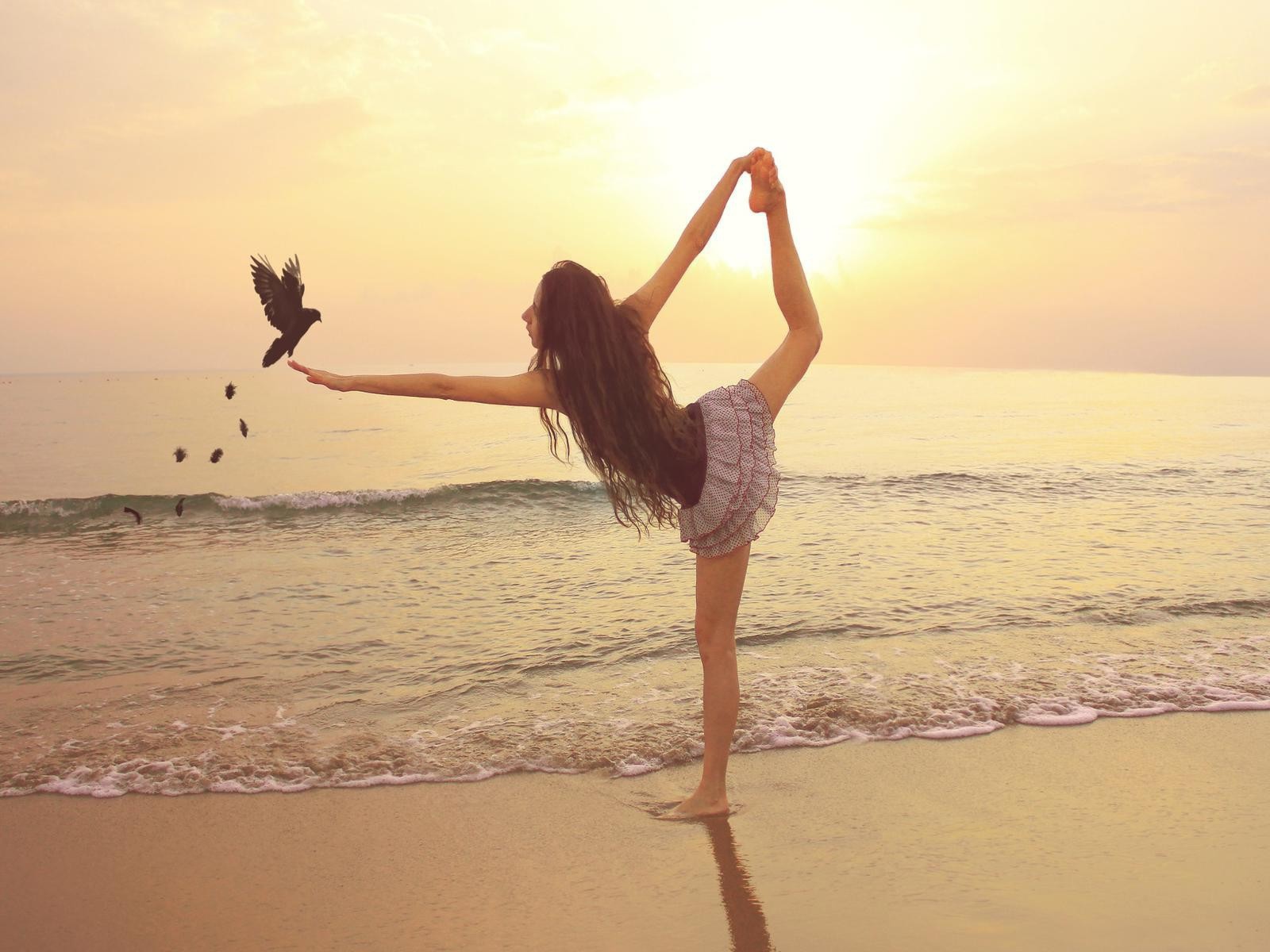 Балерина на берегу моря с птицей