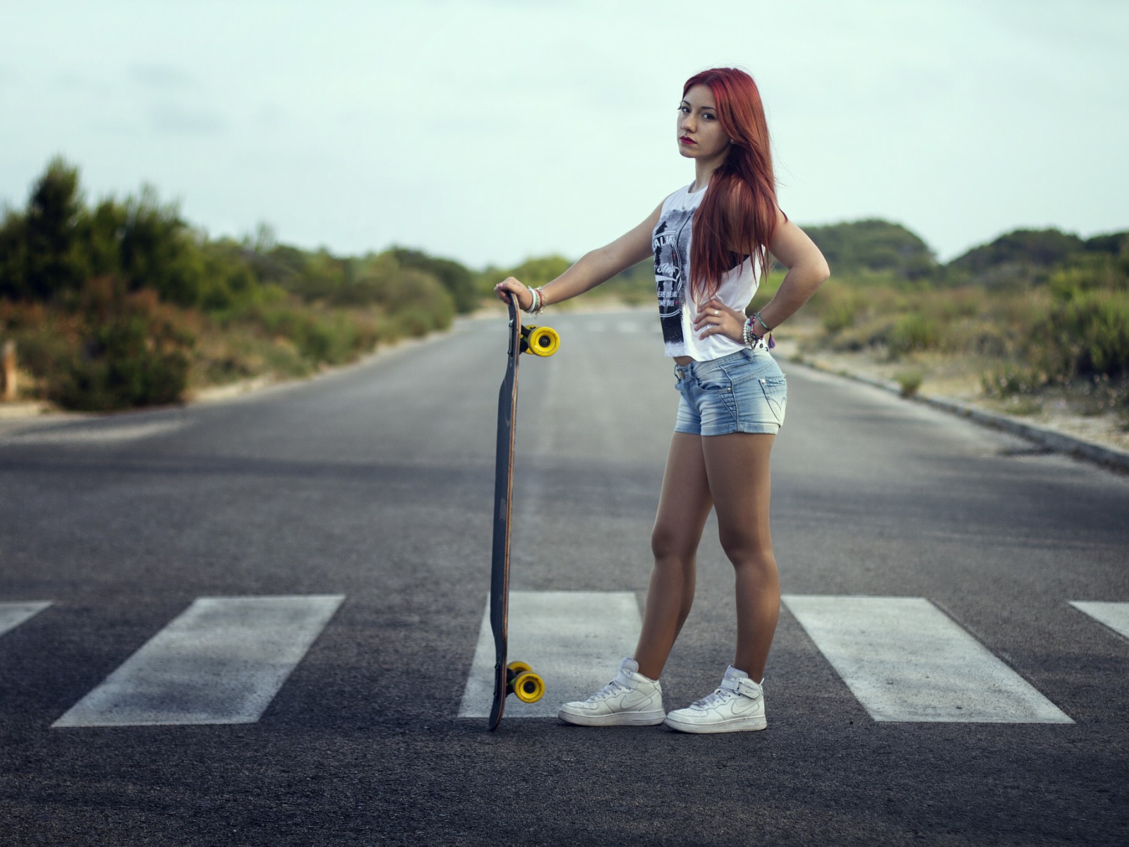 Девушка со скейтбордом стоит на переходе
