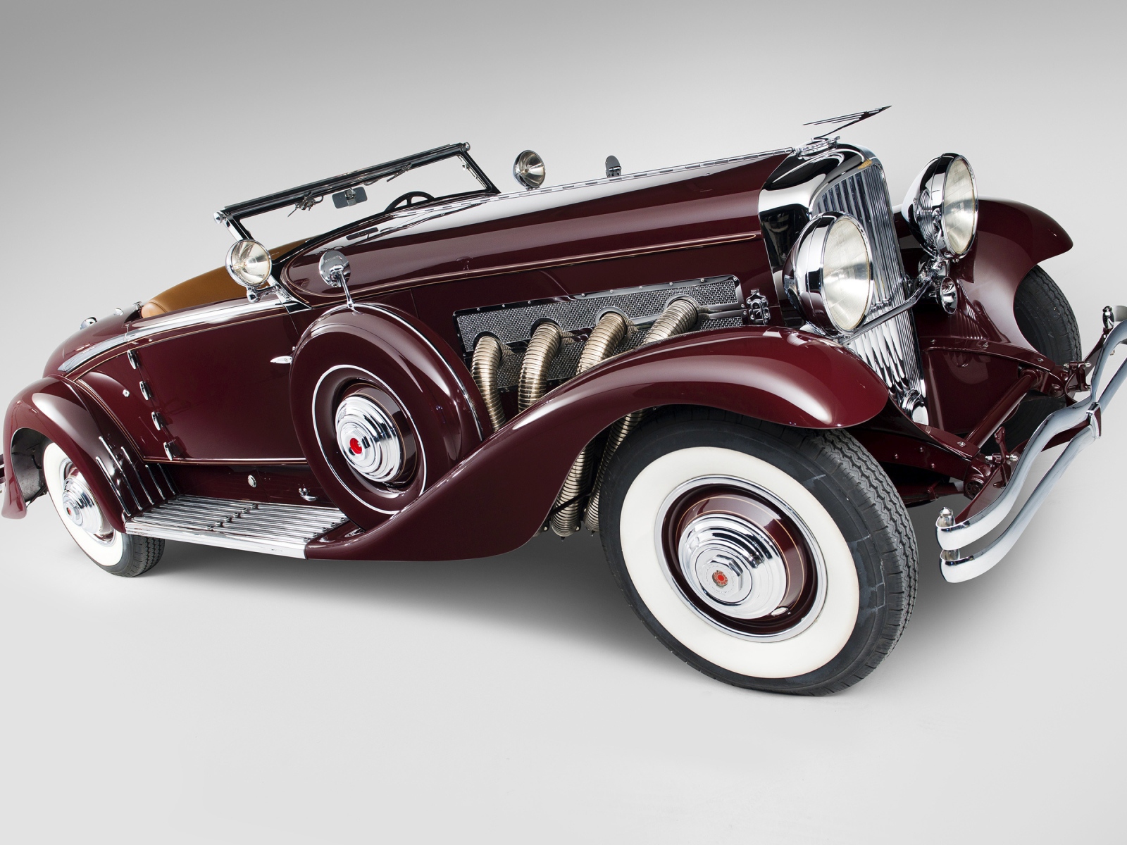 Бордовый ретро автомобиль Duesenberg Model J 530 на сером фоне