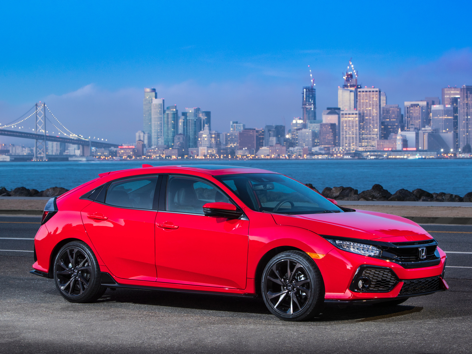 Red car Honda Civic Touring Hatchback, 2017 against the background of the city