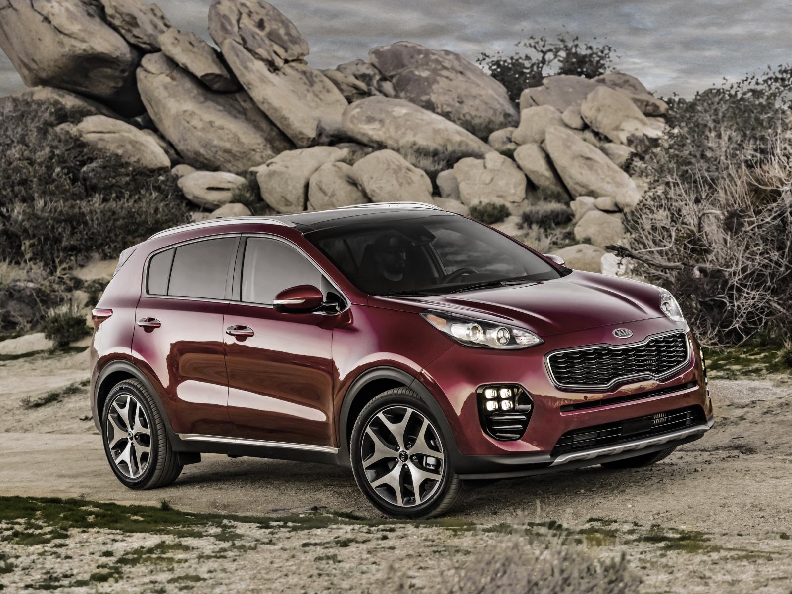 Стильный бордовый внедорожник Kia Sportage на фоне больших камней
