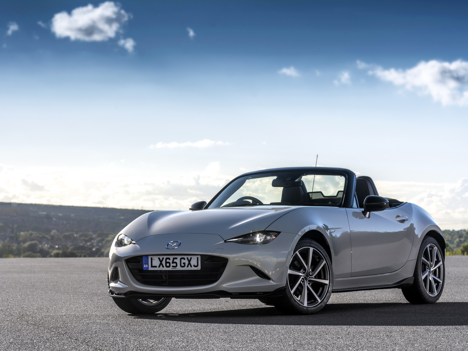 Серебристый кабриолет Mazda MX-5 на фоне красивого неба