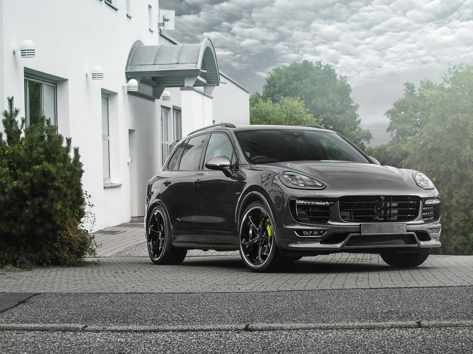 Серебристый автомобиль Porsche Cayenne стоит у дома