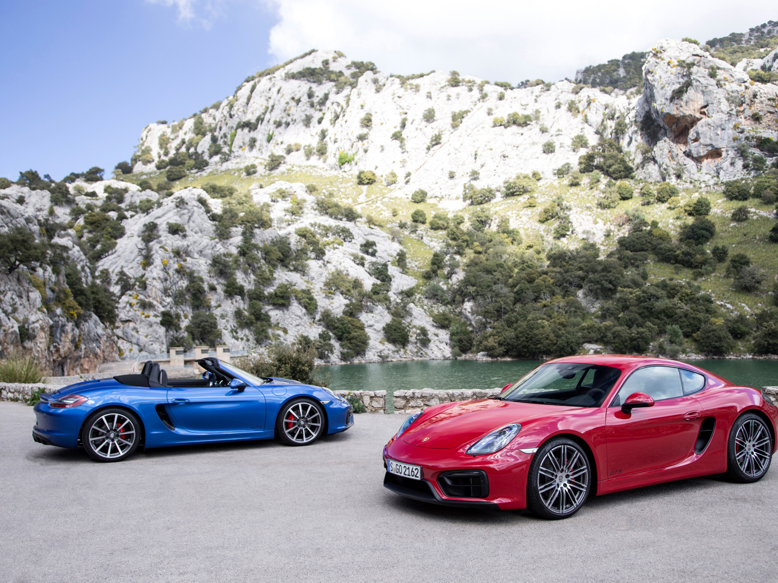 Two sports cars Porsche Boxster and Porsche Cayman GTS near water