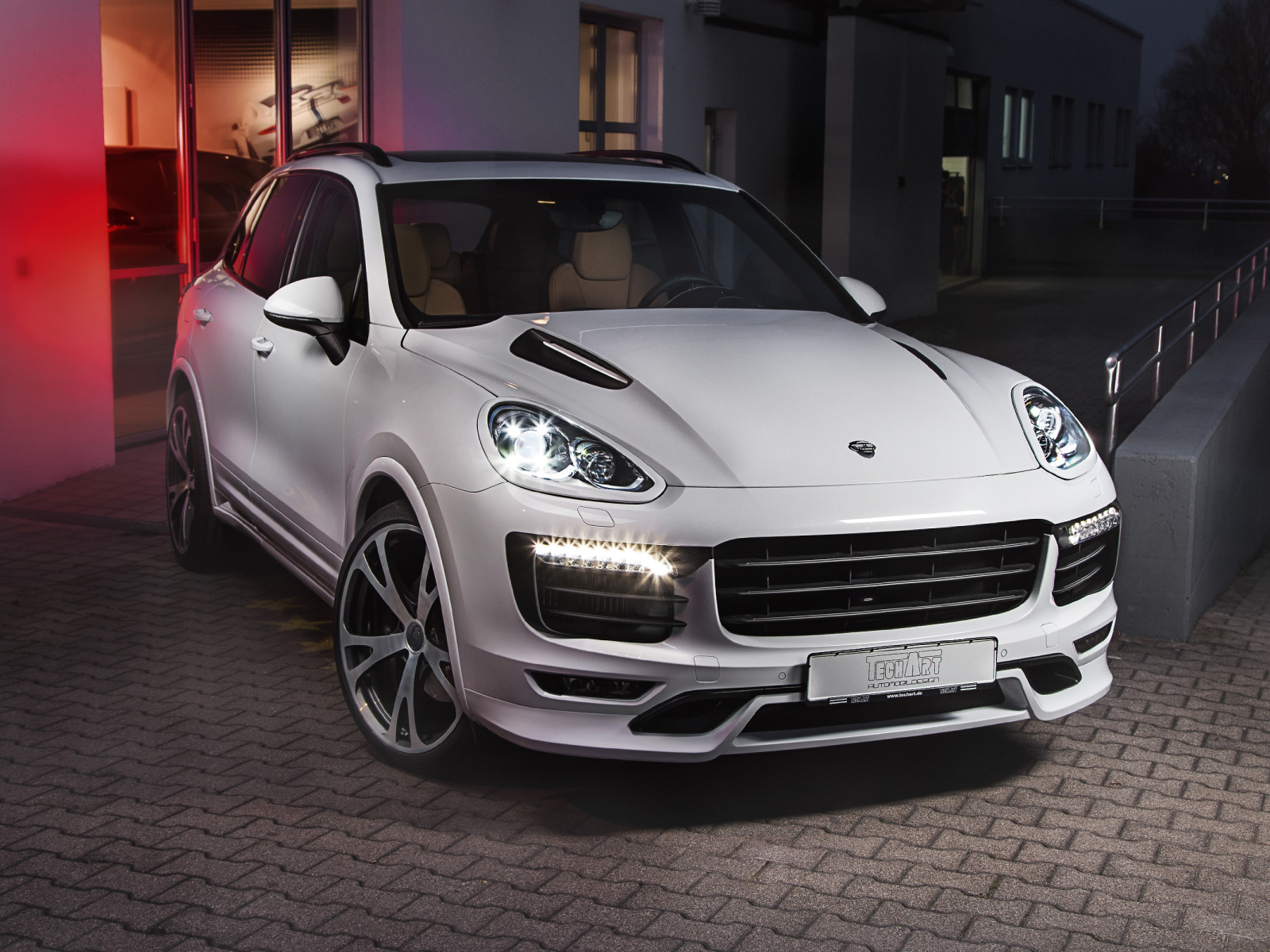 Белый внедорожник Porsche Cayenne с включенными фарами