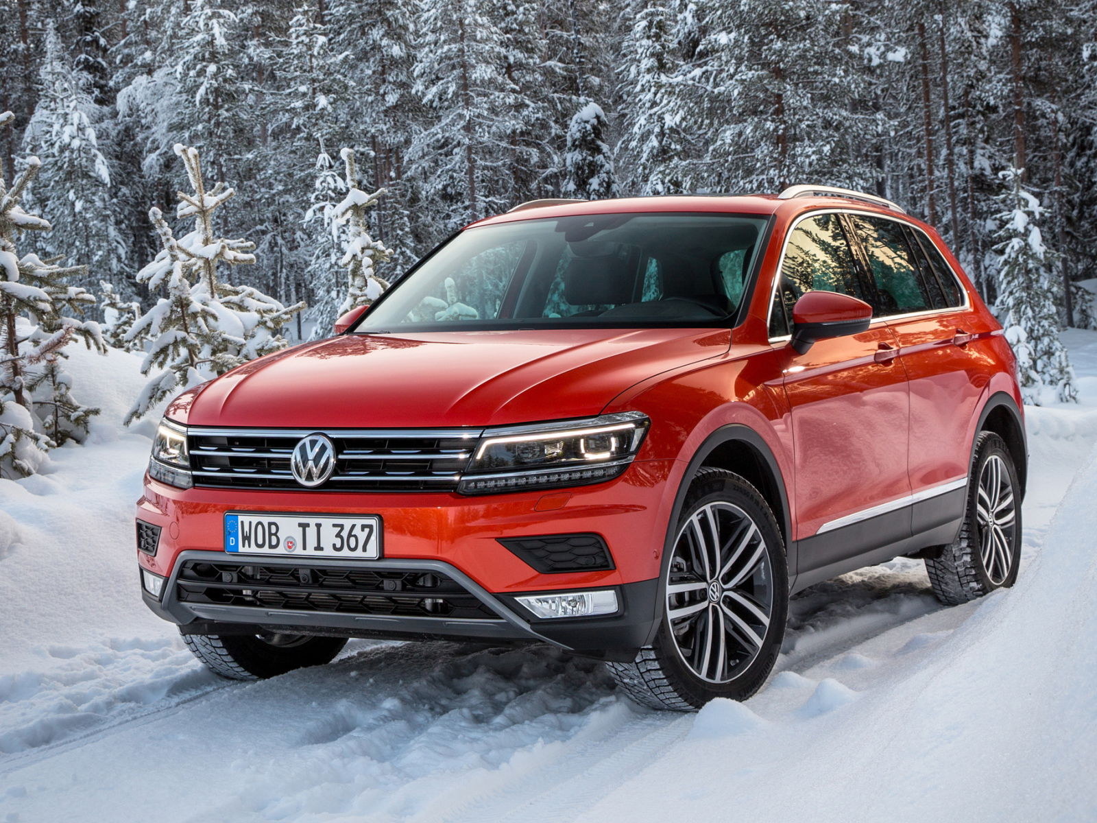 Красный Volkswagen Tiguan 2017 года в заснеженном лесу 