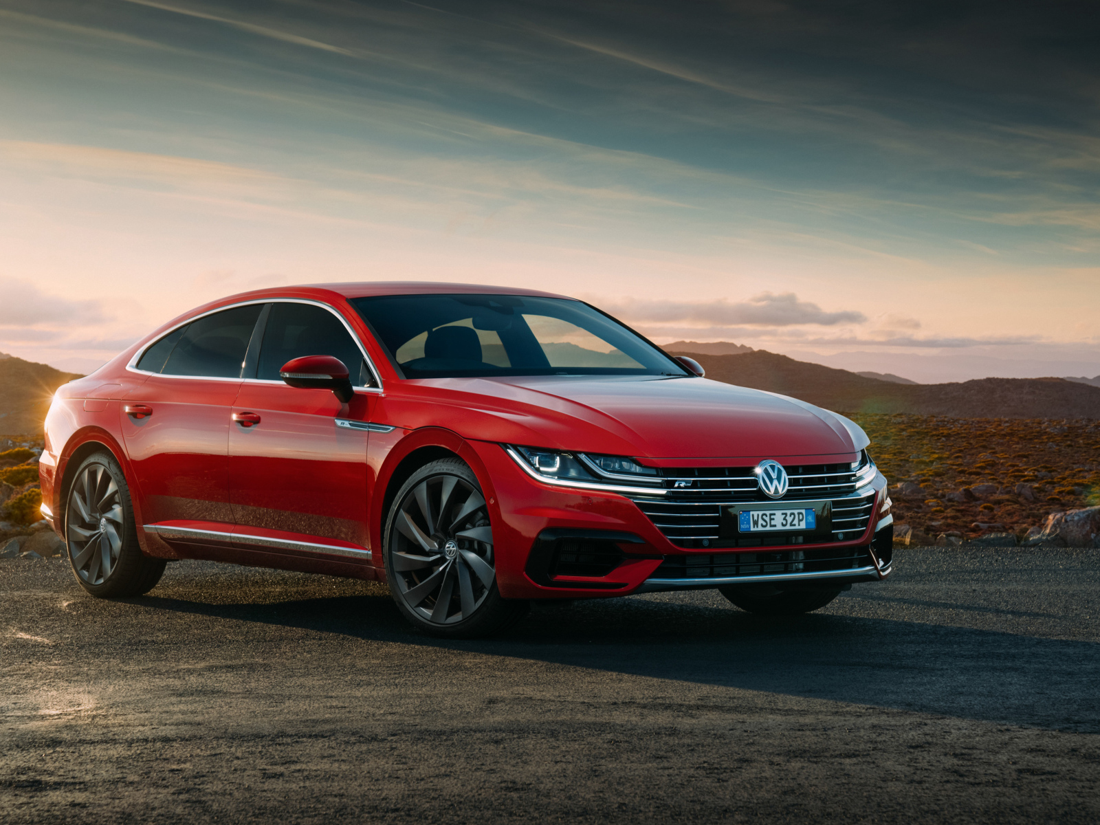 Красный автомобиль Volkswagen Arteon 4MOTION R Line, 2018 на фоне красивого неба