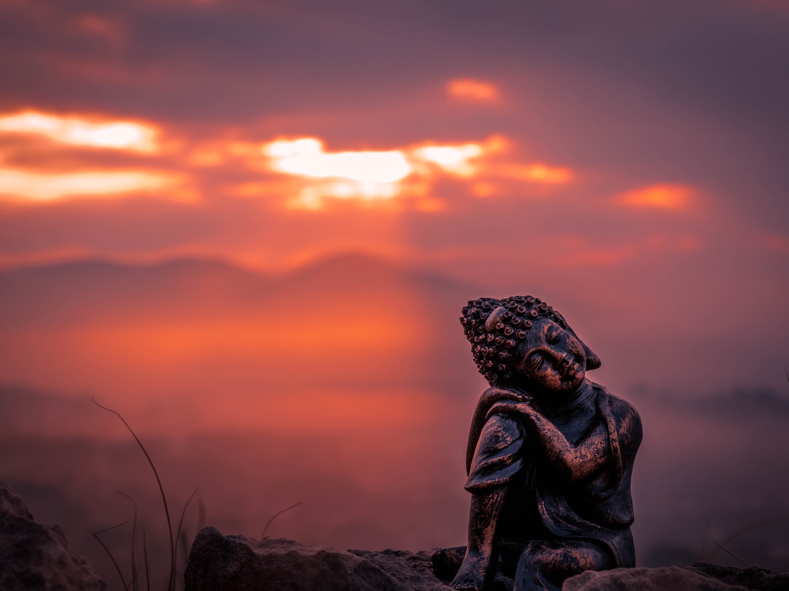 Статуя Будды на фоне солнца на закате