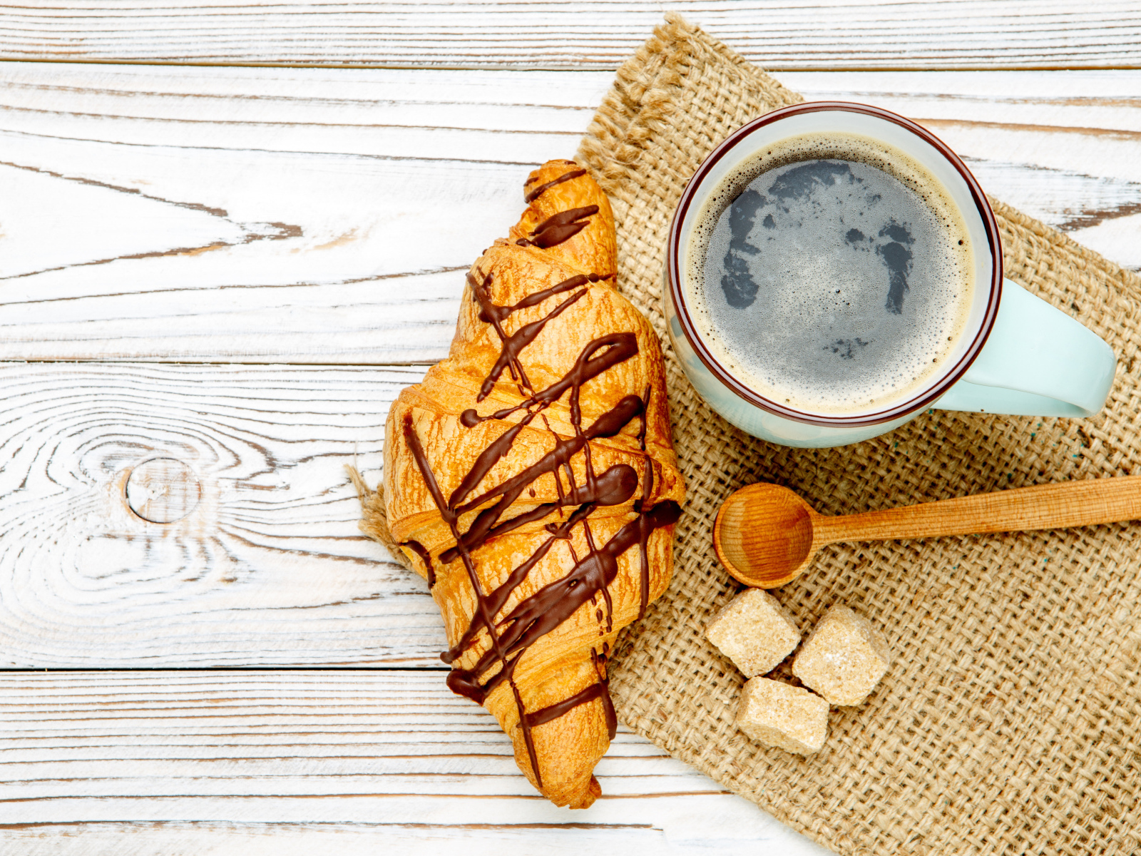 Круассан с шоколадом и чашкой кофе на столе