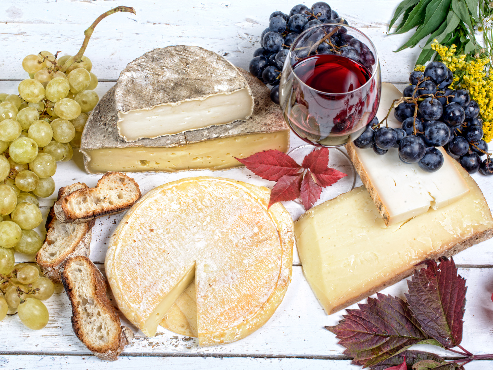 Дорогой сыр с плесенью на столе с виноградом и красным вином