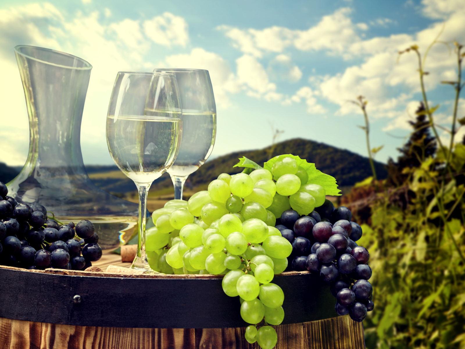 Гроздья синего и белого винограда с фужерами на деревянной бочке