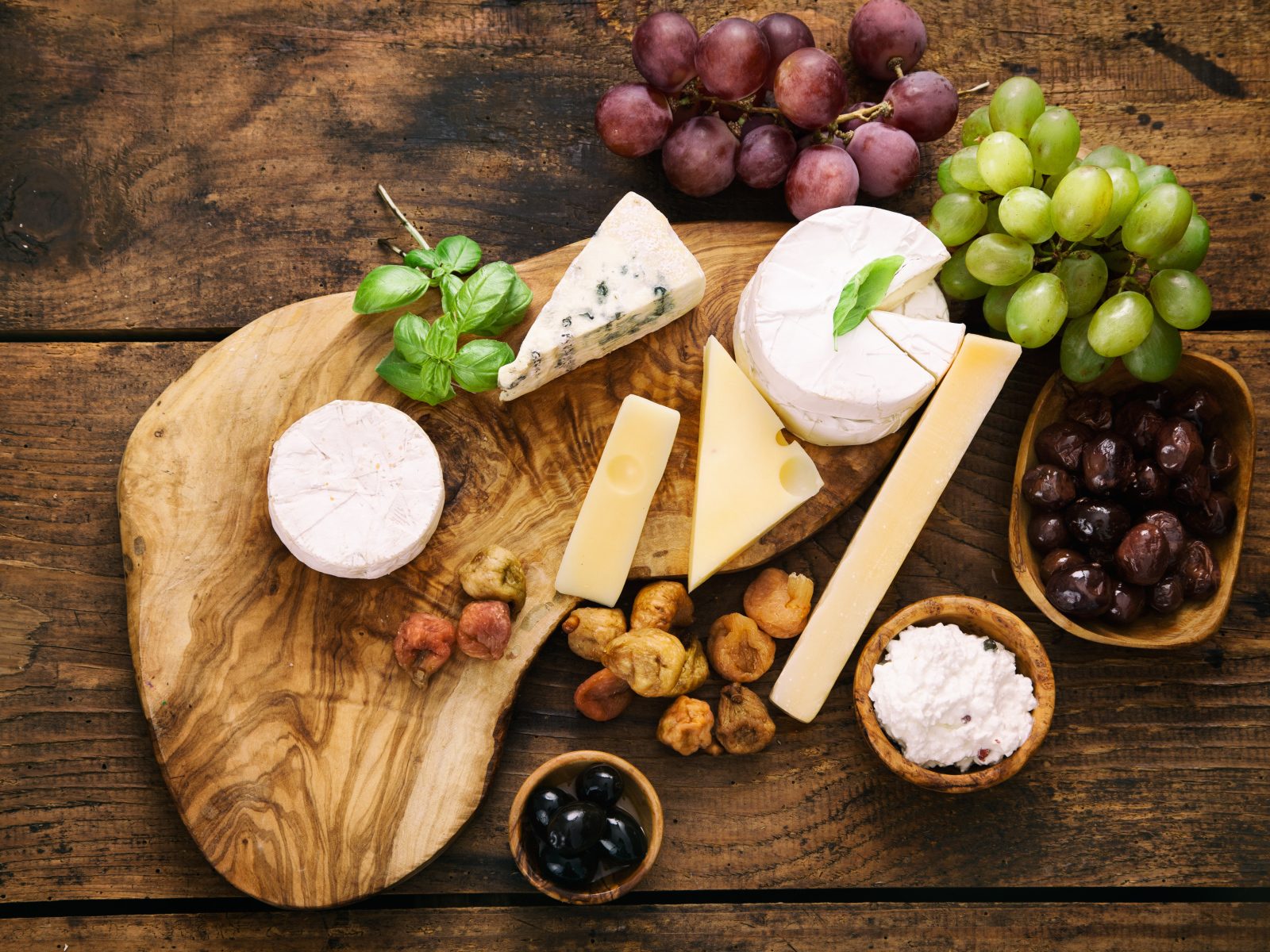 Кусочки сыра с виноградом и оливками на столе