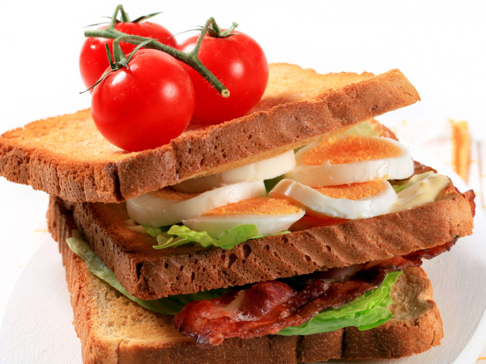 Сэндвич с беконом, яйцами и овощами на белом фоне