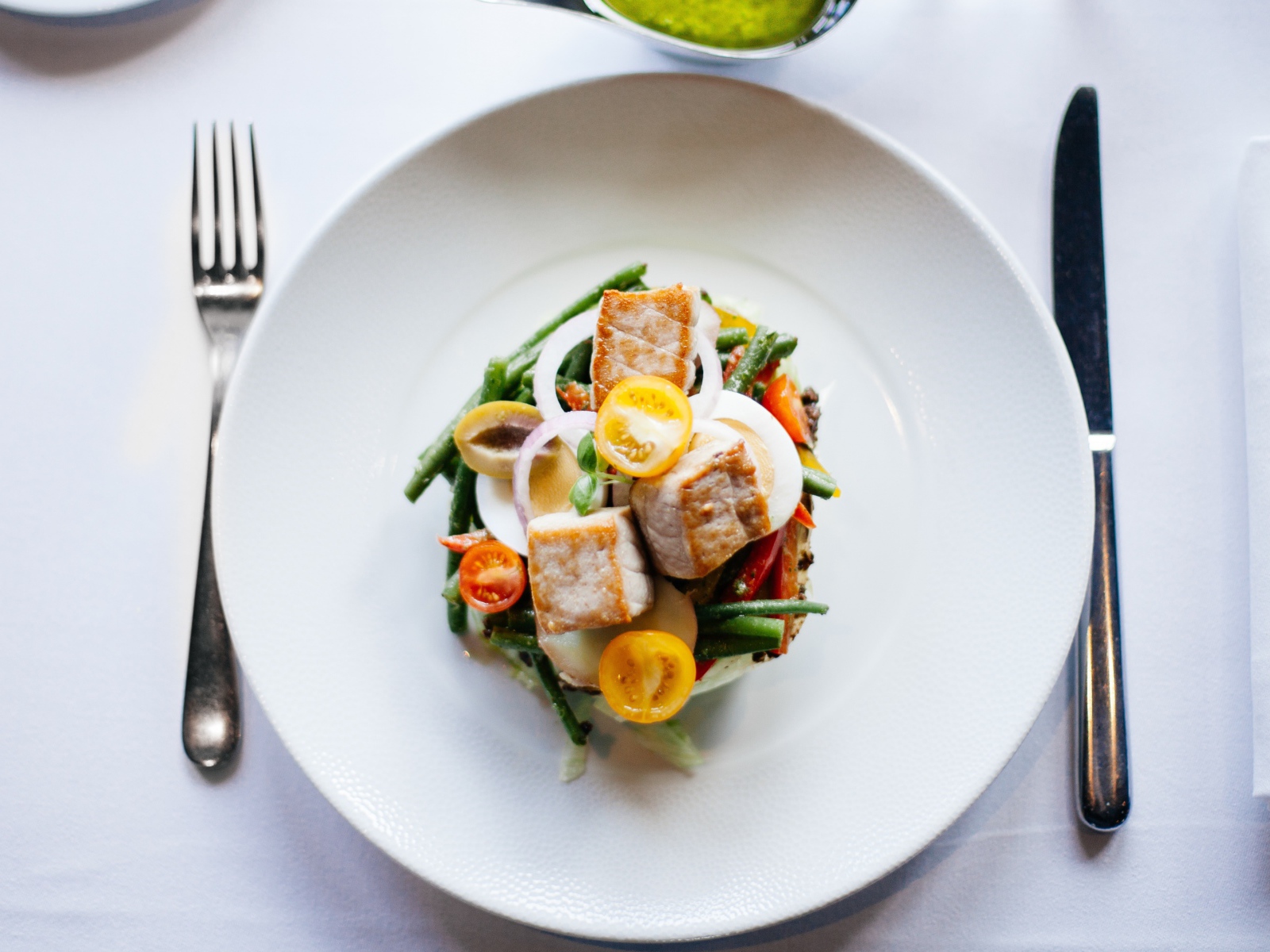 Овощной салат на белой тарелке со столовыми приборами