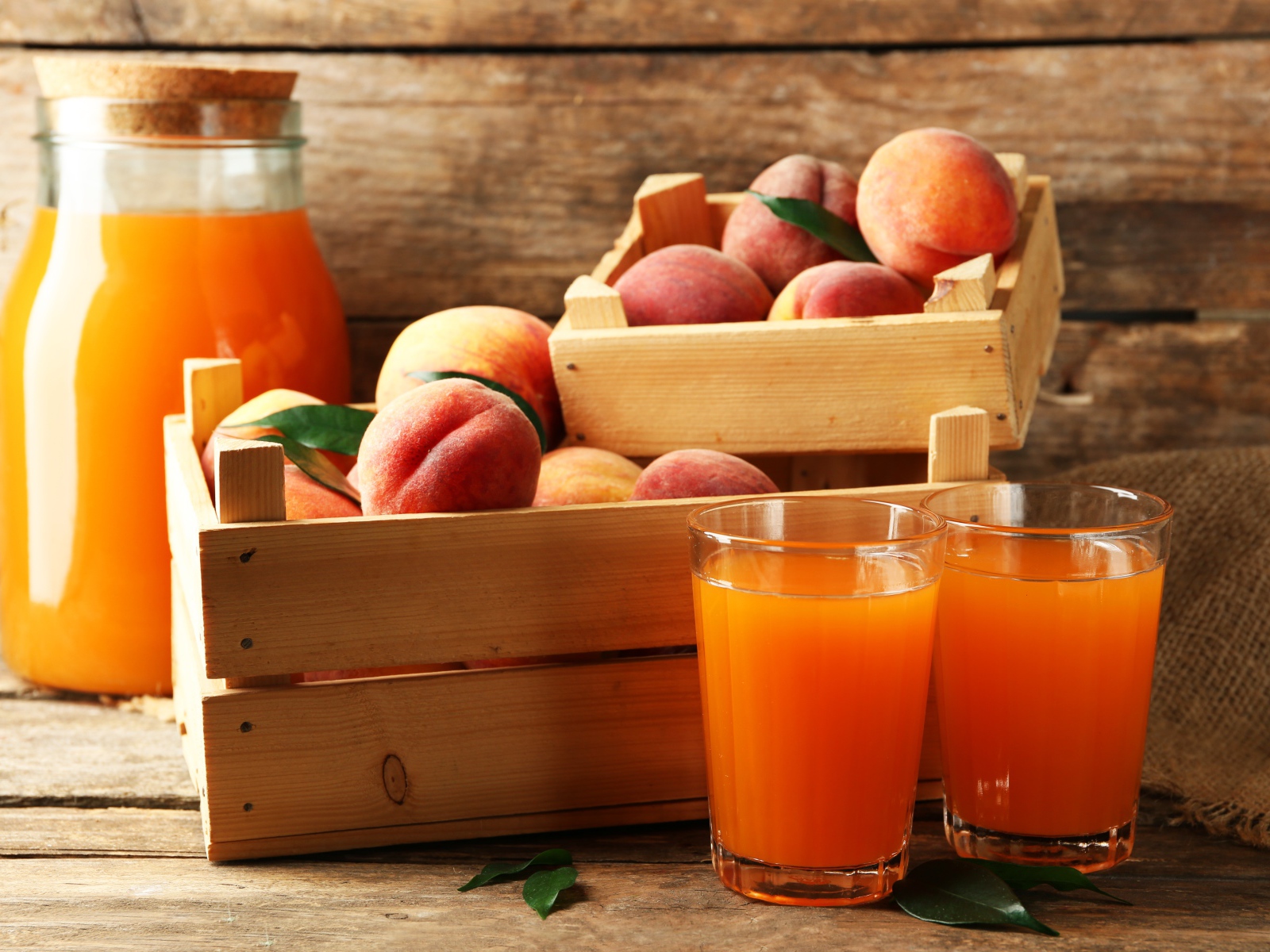 Свежие персики в деревянном ящике со свежим соком на столе