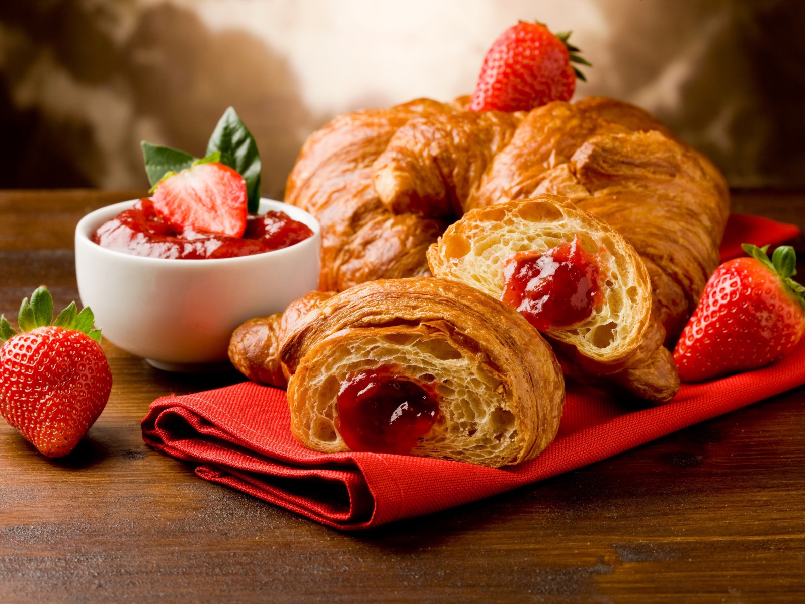Свежие круассаны с клубничным джемом и ягодами клубники на столе