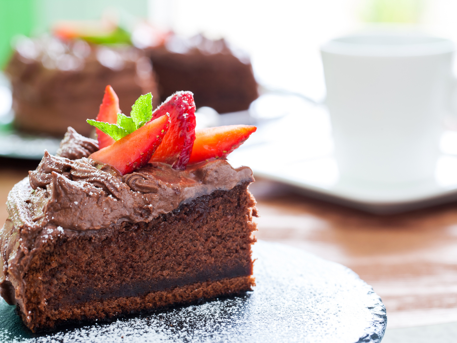 Кусок шоколадного торта с кремом и свежей клубникой 