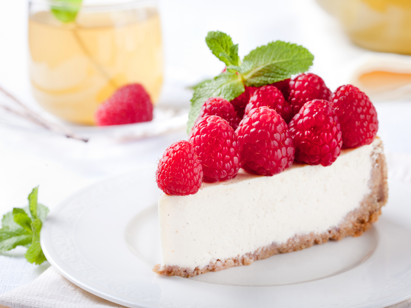 Аппетитный кусок чизкейка со свежими ягодами малины и листьями мяты