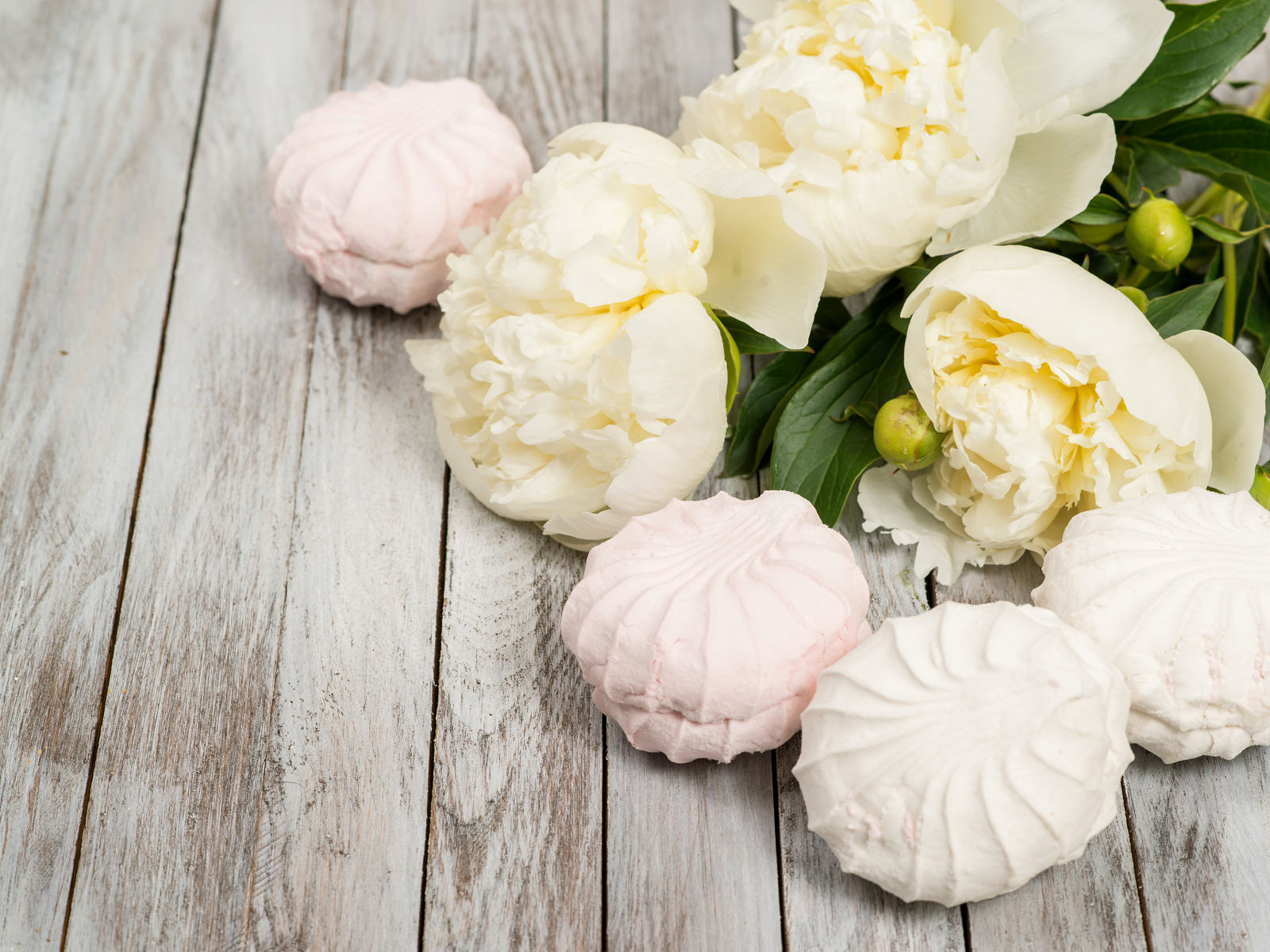 Сладкий зефир на столе с белыми пионами