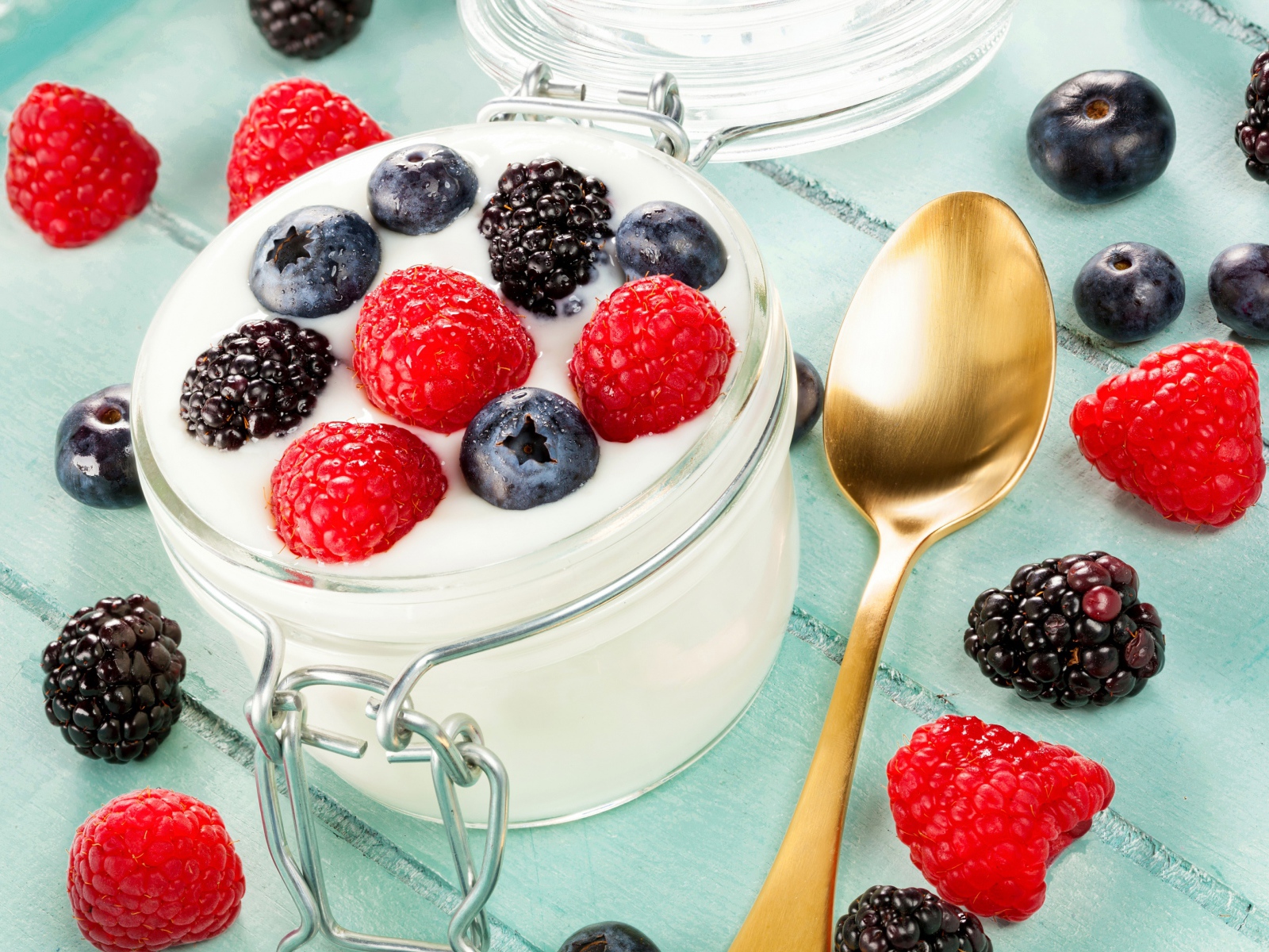 Йогурт со свежими ягодами малины, черники и ежевики в стеклянной банке на завтрак
