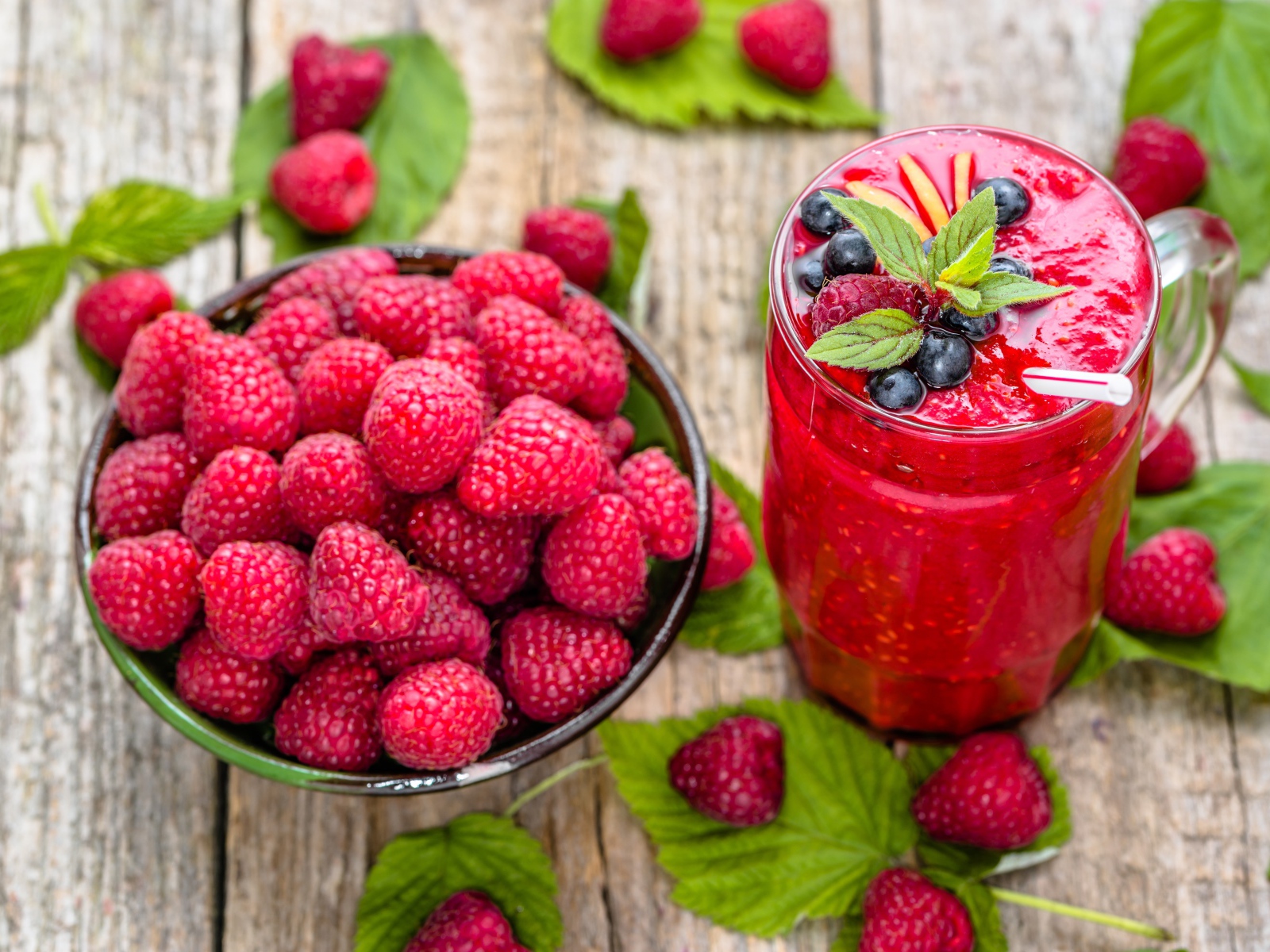 Стакан ягодного смузи на столе со свежими ягодами малины