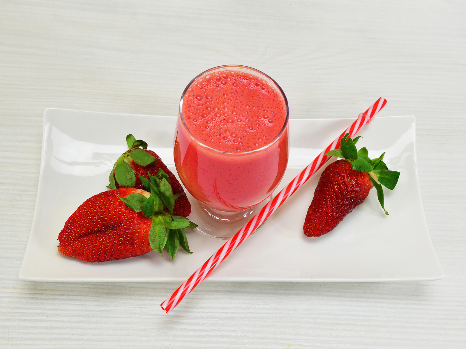 Бокал клубничного коктейля со свежей клубникой и трубочкой