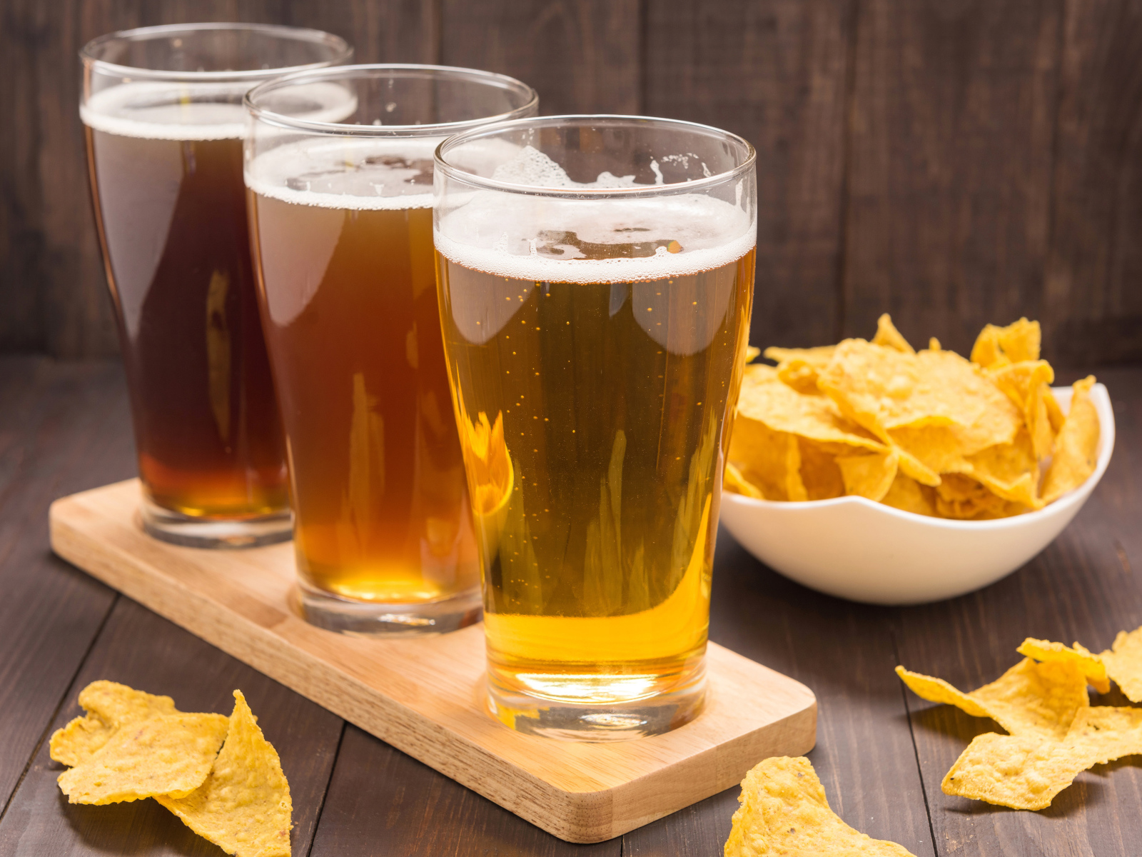 Три стакана пива на столе с чипсами