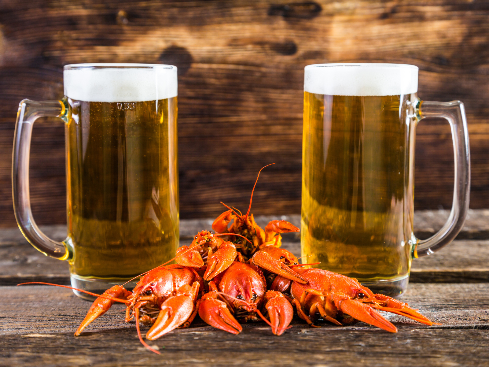 Два бокала пива с красными раками на столе