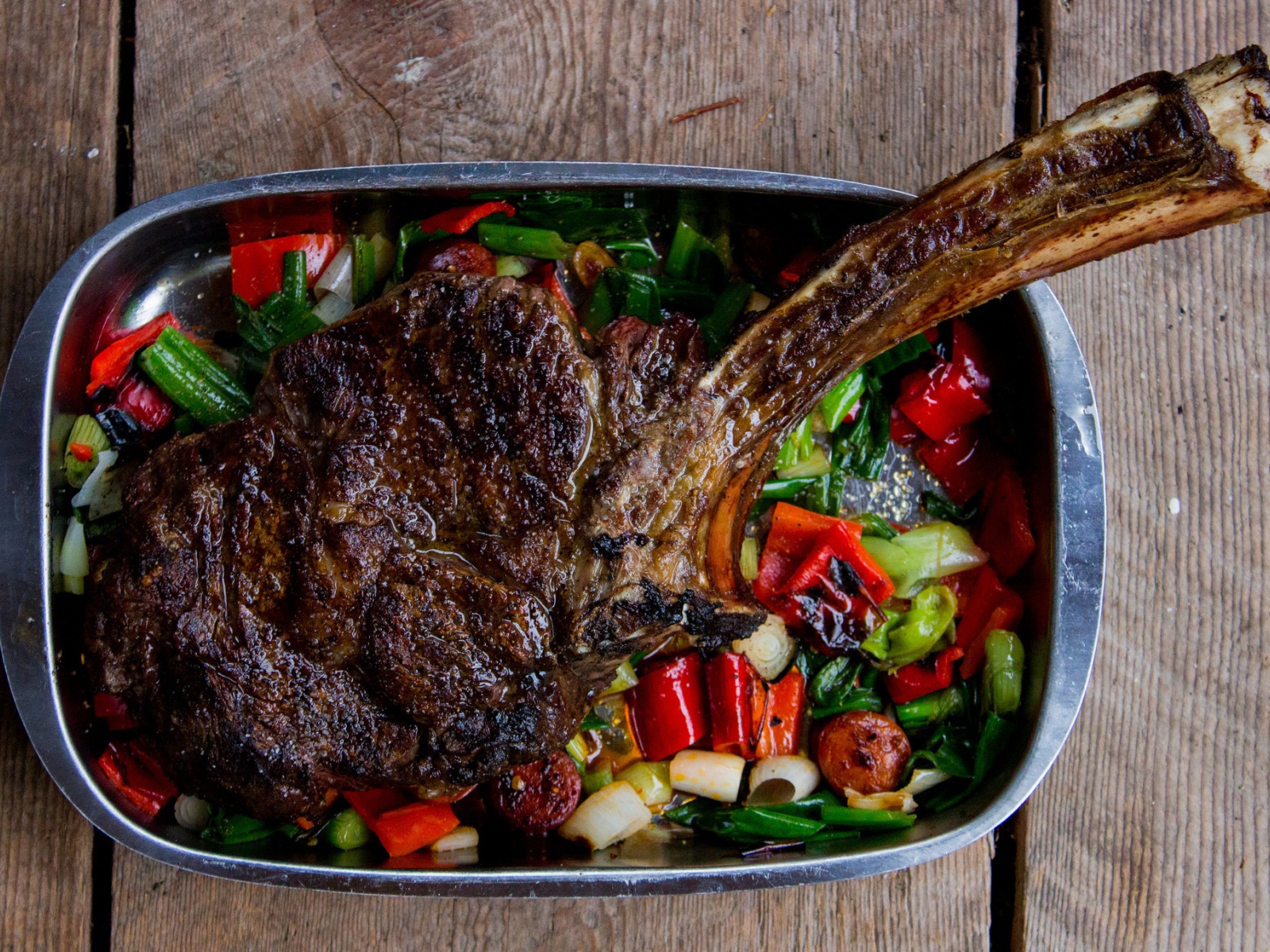 Кусок жареного мяса на ребрышке с овощами