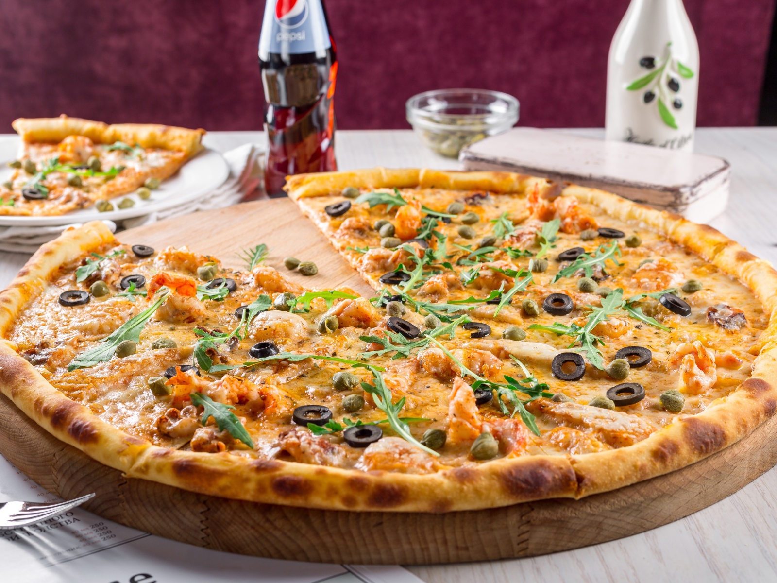 Пицца с оливками на столе с бутылкой пепси