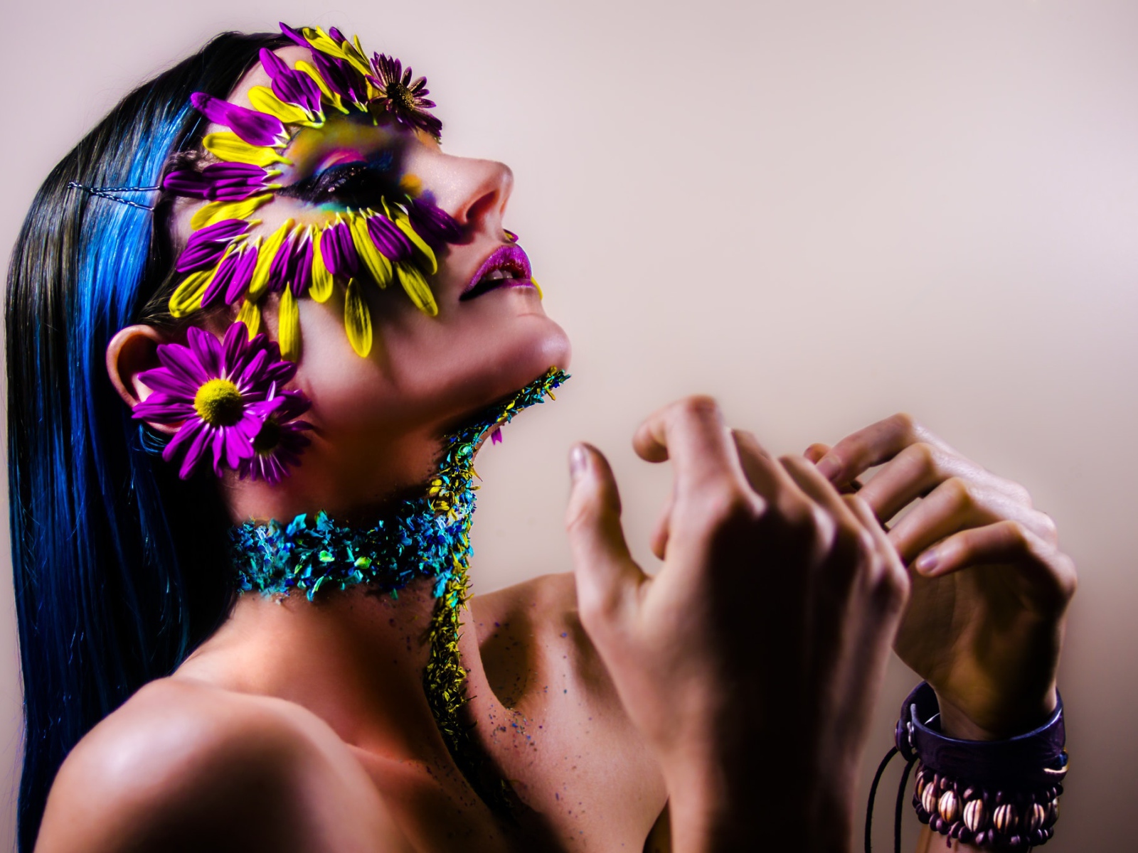 Девушка с украшенным лепестками цветов лицом и ярким макияжем