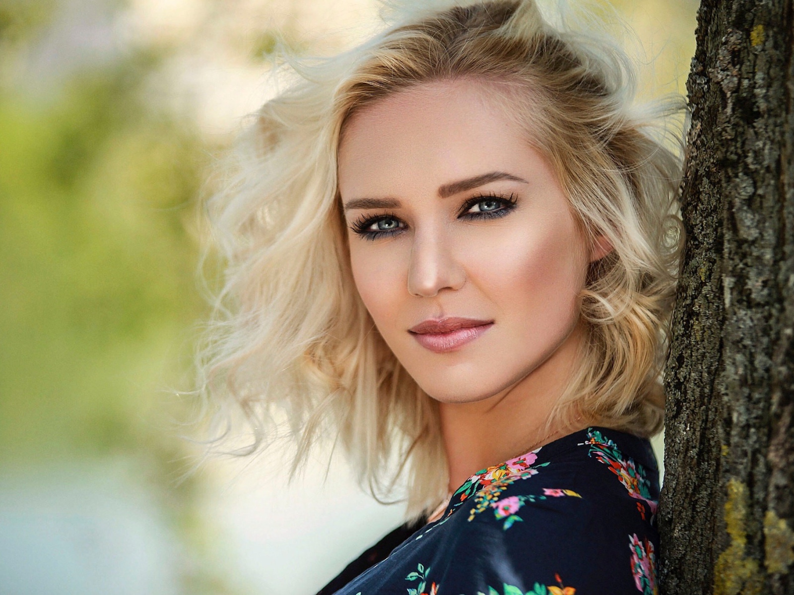 Красивая блондинка с голубыми глазами у дерева 